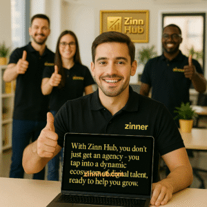A Group Of Smiling Freelancers In Matching Black Polo Shirts With Gold &Quot;Zinner&Quot; Logos Give Thumbs-Up In A Modern Office. In The Foreground, One Holds A Laptop Displaying The Message: “With Zinn Hub, You Don’t Just Get An Agency—You Tap Into A Dynamic Ecosystem Of Digital Talent, Ready To Help You Grow.” A Framed Gold Zinn Hub Logo Hangs On The Wall Behind Them.