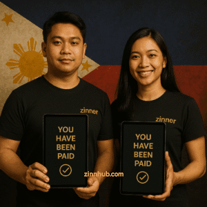 Two Zinn Hub Filipino Freelancers In Black Zinner Shirts Holding Tablets With 'You Have Been Paid' And Green Checkmark, Standing In Front Of The Philippine Flag.