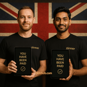 Two Multicultural Zinn Hub Uk Freelancers In Black Zinner Shirts Holding Tablets With 'You Have Been Paid' And Green Checkmark, Standing In Front Of The Union Jack.