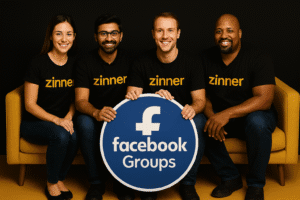 Four Smiling Freelancers In Black &Quot;Zinner&Quot; Shirts And Jeans Sit On A Gold Sofa Holding A Blue &Quot;Facebook Groups&Quot; Sign.